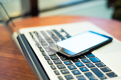 Image of Cellphone on laptop computer in coffee shop