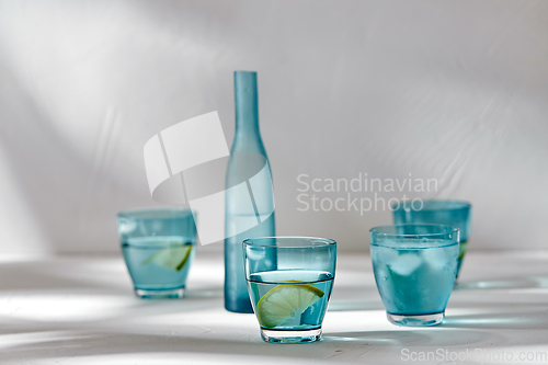 Image of glasses with water and lemons on white background