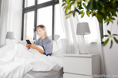 Image of young woman with smartphone in bed in morning