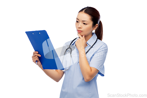 Image of pensive asian female doctor with clipboard