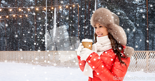 Image of happy woman with coffee cup over winter ice rink