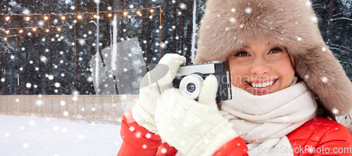 Image of happy woman with film camera in winter at ice rink