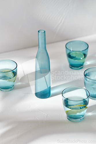 Image of glasses with water and lemons on white background