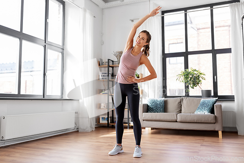 Image of smiling young woman exercising at home