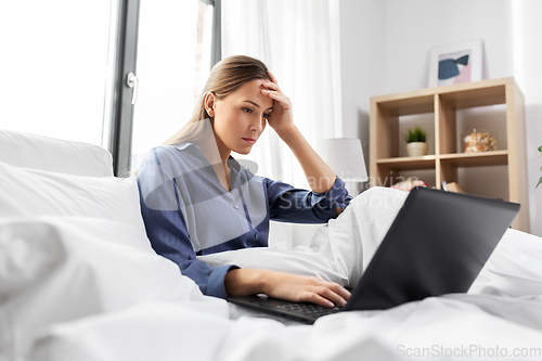 Image of stressed young woman with laptop in bed at home