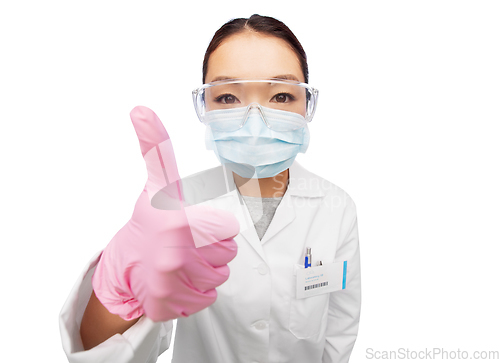 Image of asian female doctor in mask showing thumbs up