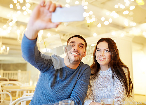 Image of couple taking smartphone selfie at cafe restaurant