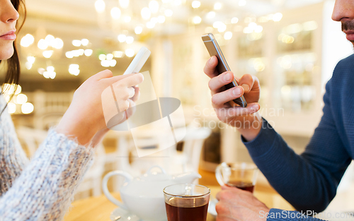 Image of close up of couple with smartphones at cafe