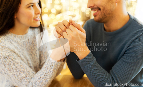 Image of happy couple holding hands at restaurant or cafe