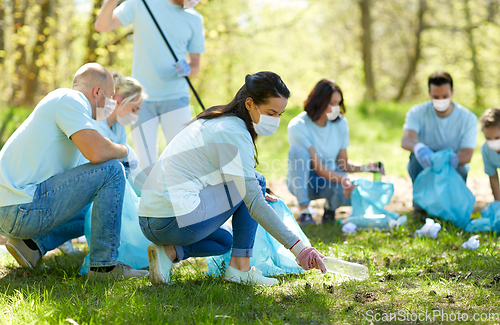 Image of volunteers in masks cleaning park from garbage