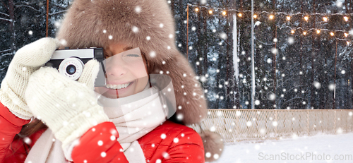 Image of happy woman with film camera in winter at ice rink