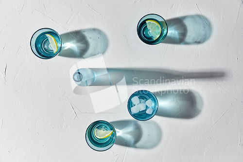 Image of glasses with water and lemons on white background