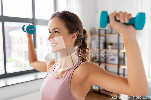 Image of smiling young with dumbbells exercising at home