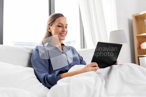 Image of young woman with tablet pc in bed at home bedroom