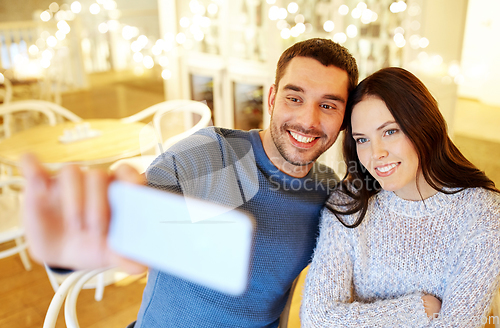 Image of couple taking smartphone selfie at cafe restaurant