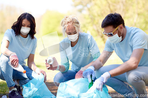 Image of volunteers in masks cleaning park from garbage