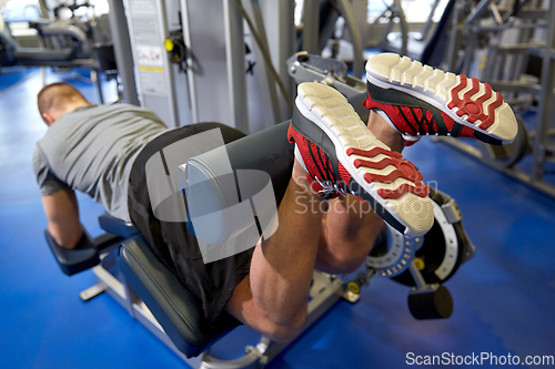 Image of man flexing leg muscles on gym machine