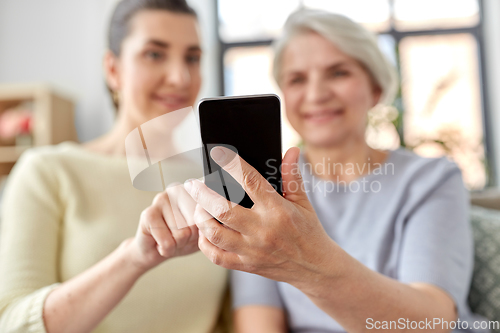 Image of daughter and senior mother with smartphone at home