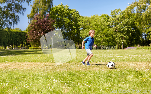 Image of happy little boy with ball playing soccer at park