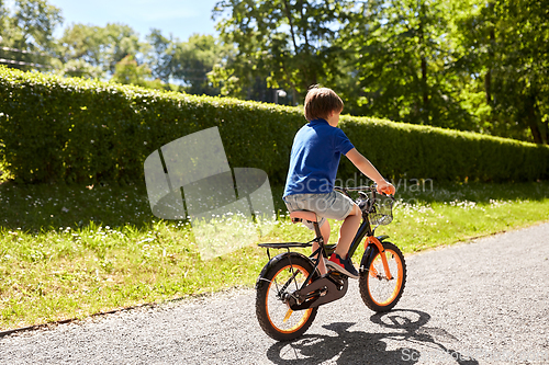 Image of little boy riding bicycle at summer park