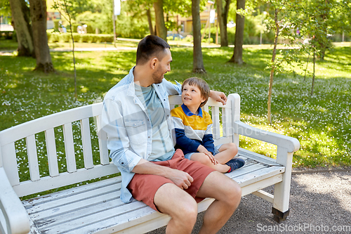 Image of father with son sitting on park bench and talking