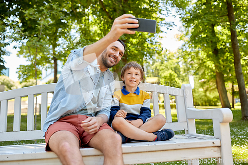 Image of father and son taking selfie with phone at park