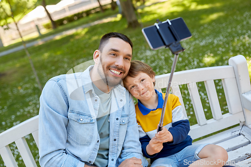 Image of father and son taking selfie with phone at park