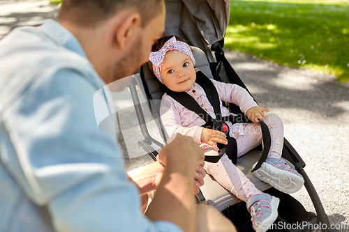 Image of happy father with child in stroller at summer park