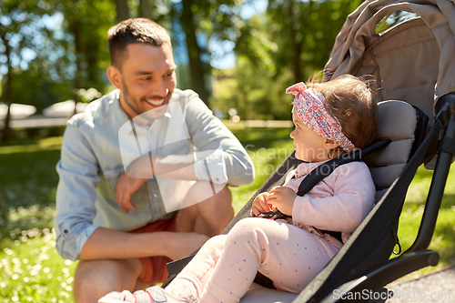 Image of happy father with child in stroller at summer park