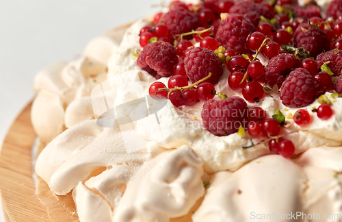 Image of pavlova meringue cake with berries on wooden board