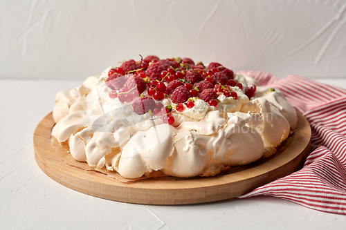 Image of pavlova meringue cake with berries on wooden board