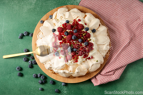 Image of pavlova meringue cake with berries on wooden board