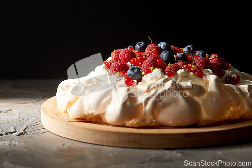 Image of pavlova meringue cake with berries on wooden board