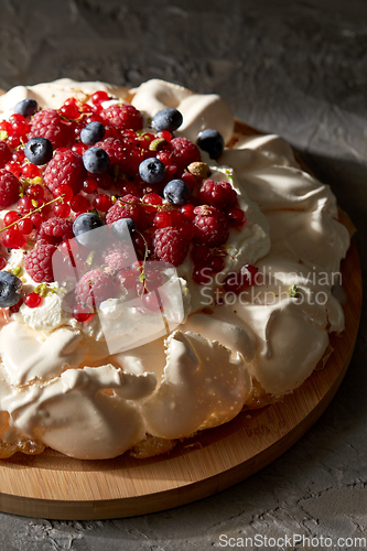 Image of pavlova meringue cake with berries on wooden board