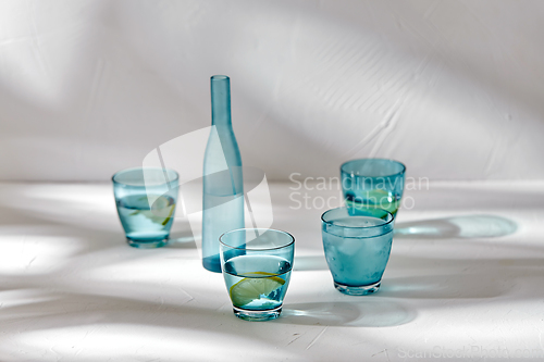 Image of glasses with water and lemons on white background