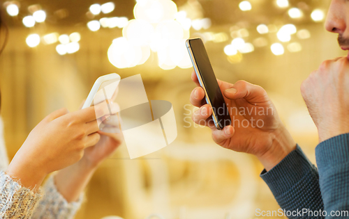 Image of close up of couple with smartphones at cafe