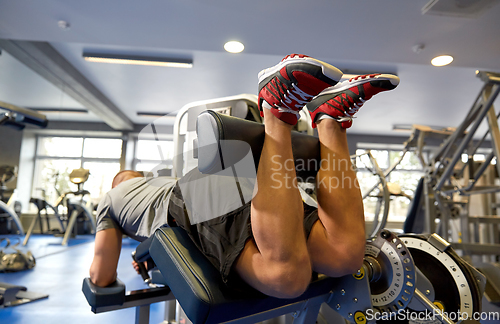 Image of man flexing leg muscles on gym machine