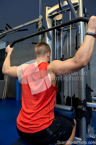 Image of close up of man exercising on cable machine in gym