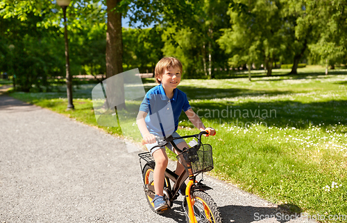 Image of happy little boy riding bicycle at summer park