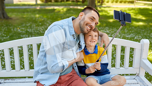 Image of father and son taking selfie with phone at park