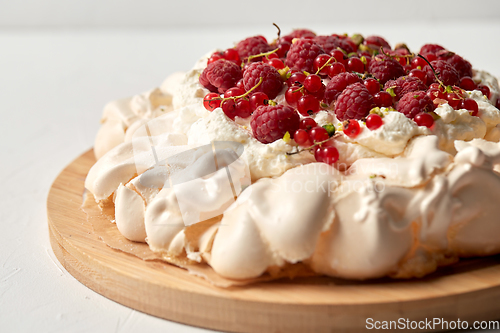 Image of pavlova meringue cake with berries on wooden board