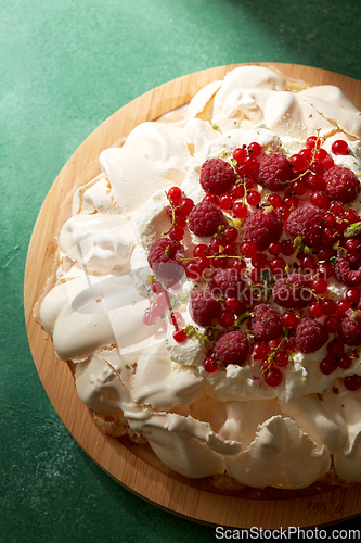 Image of pavlova meringue cake with berries on wooden board