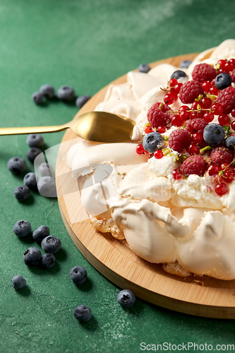 Image of pavlova meringue cake with berries on wooden board