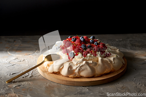 Image of pavlova meringue cake with berries on wooden board