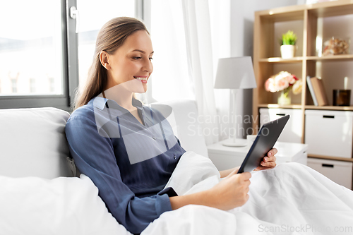 Image of young woman with tablet pc in bed at home bedroom