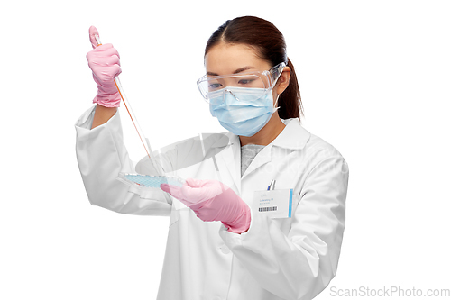 Image of asian female scientist in mask working on vaccine