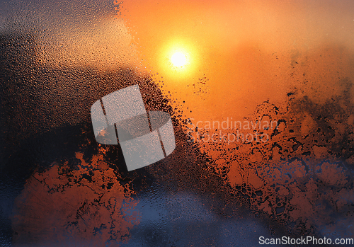 Image of Ice patterns, water drops and sunlight on a winter window glasss