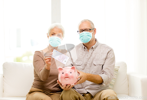 Image of old couple in masks putting money into piggy bank