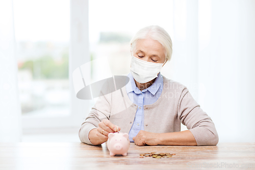 Image of old woman in mask putting coin into piggy bank