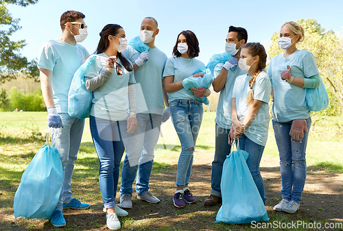 Image of volunteers in masks with garbage bags in park